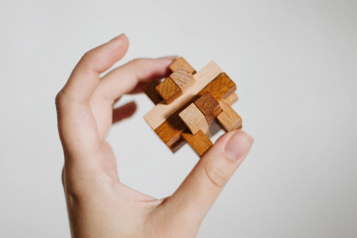 A hand holding an assembled interlocking birch puzzle, no glue used.