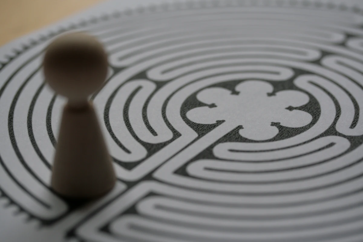 A printed labyrinth sheet with a wooden pawn resting one turn short of the centre.