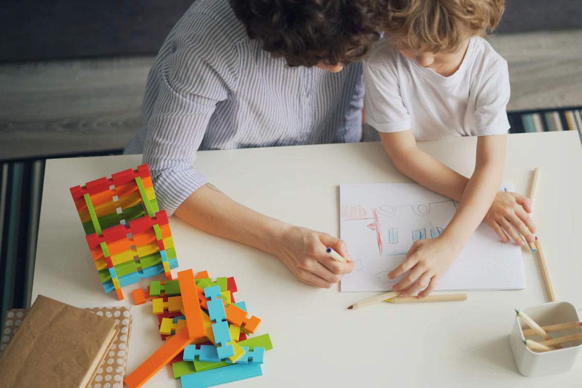A parent and child mid-build, parts still in their station tray, plan sheet under the frame.